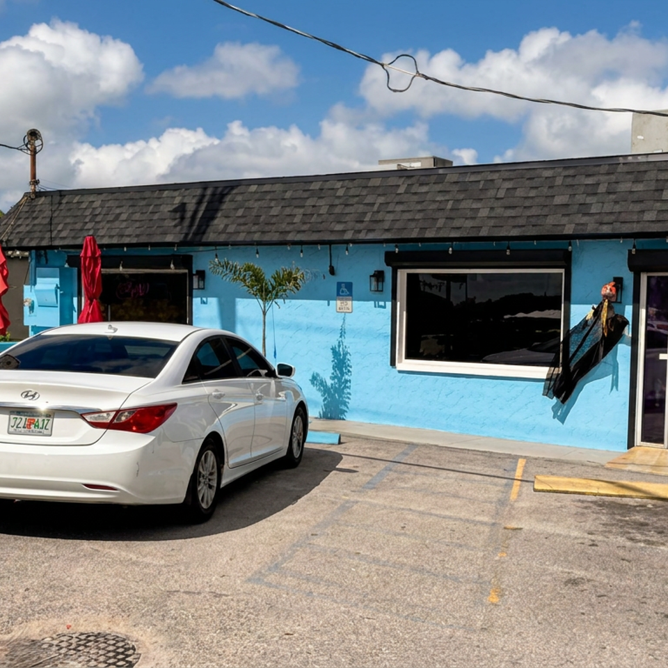 Bright blue Rincon Cubano restaurant and cafeteria exterior with outdoor seating, red umbrellas, parked cars, and daily special sign.