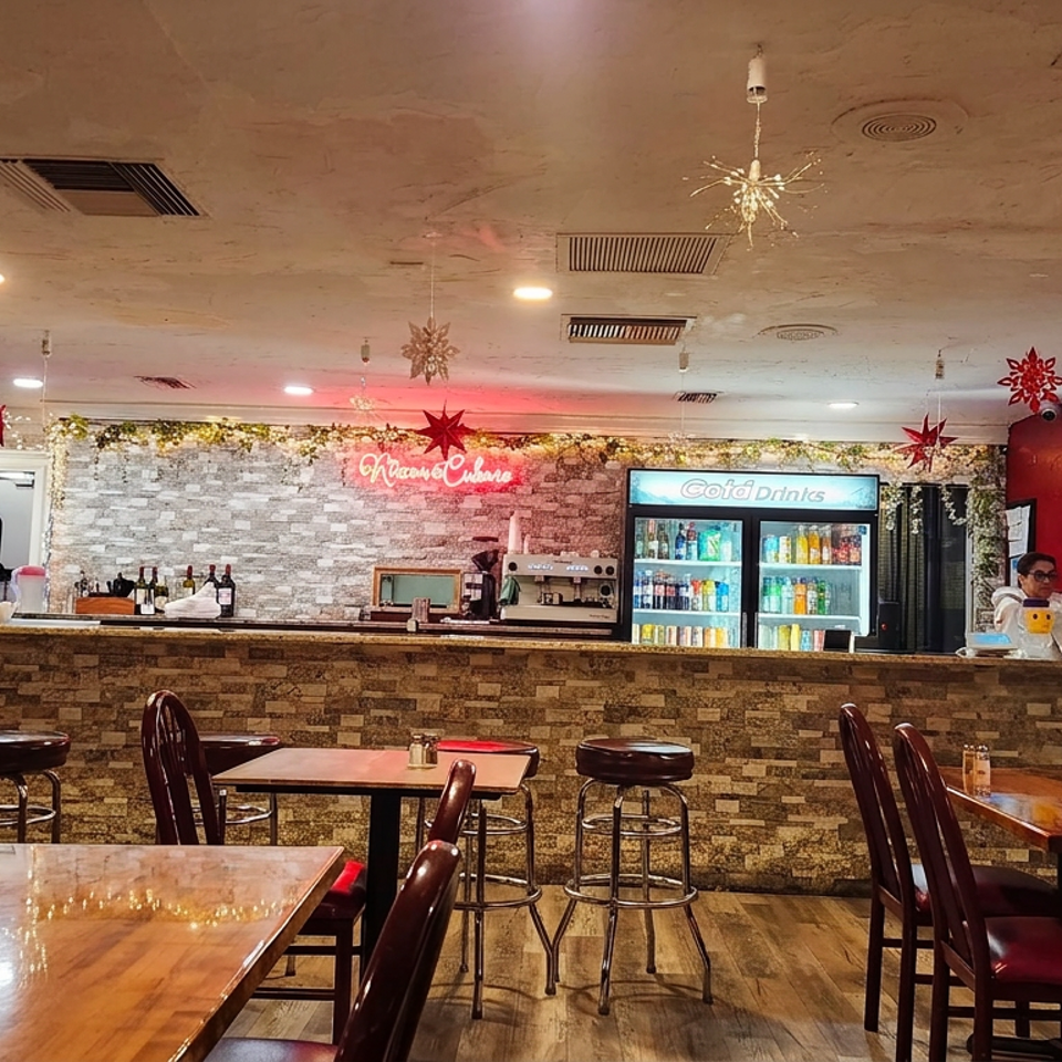 Warmly lit Chinese restaurant dining room with wooden tables, stone bar, beverage cooler, festive red decorations, and staff behind the counter.